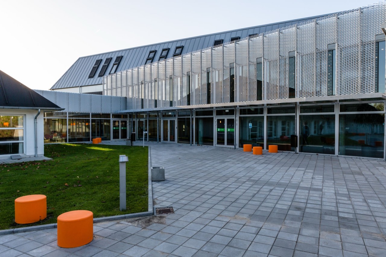 UCN Aalborg campus — modern glass building with the university's signature orange seats in the courtyard